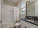 Bright bathroom featuring a vanity with dark countertops, a bathtub with a shower, and modern fixtures at 6109 Marsh Trail Dr, Odessa, FL 33556