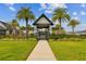 Clubhouse entrance features a covered entryway, black fencing, and a lush green lawn with palm trees at 6109 Marsh Trail Dr, Odessa, FL 33556