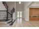 Bright foyer with wood-look tile flooring, dark wood staircase, and decorative built-in cabinet at 6109 Marsh Trail Dr, Odessa, FL 33556