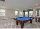 Spacious game room features a classic blue felt pool table, plush carpet, and large windows with lake views at 6109 Marsh Trail Dr, Odessa, FL 33556