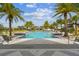 Community pool with lush landscaping, palm trees, lounge chairs and other yellow accent furniture at 6109 Marsh Trail Dr, Odessa, FL 33556