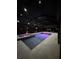 Illuminated pool at night, featuring a spa and lounge chairs under a screened enclosure at 6109 Marsh Trail Dr, Odessa, FL 33556