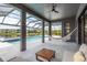 Covered outdoor pool area with a hammock, ceiling fan, and view of the backyard and lake at 6109 Marsh Trail Dr, Odessa, FL 33556