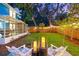 Lush backyard with a charming deck area, ambient lighting, and a view of the screened porch, creating a relaxing retreat at 661 14Th S Ave, St Petersburg, FL 33701