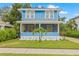 Charming two-story blue home with a screened porch, a well-manicured lawn, and a palm tree at 661 14Th S Ave, St Petersburg, FL 33701