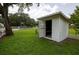 Exterior shot of the outdoor shed, nestled in a green yard with trees at 7240 Ottley St, Zephyrhills, FL 33541