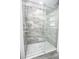 A stylish bathroom shower stall features marble-look tile and a glass door at 913 Spindle Palm Way, Apollo Beach, FL 33572