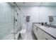 Modern bathroom with a glass-enclosed shower featuring marble tile, a toilet, and a vanity with ample counter space at 1 Seaside Ln # 302, Belleair, FL 33756