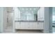 Bathroom featuring a double sink vanity, large mirror, and a separate shower with marble tiling at 1 Seaside Ln # 302, Belleair, FL 33756