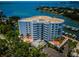 An exterior angle showcasing the condo building and its many balconies with waterfront views surrounded by mature trees at 1 Seaside Ln # 302, Belleair, FL 33756