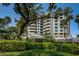 Exterior view of condo building with a lush green landscape with trees and bushes surrounding the building at 1 Seaside Ln # 302, Belleair, FL 33756