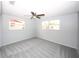 A bright bedroom featuring neutral walls, carpet, two windows, and a ceiling fan at 10740 Oldham Rd, Port Richey, FL 34668
