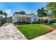 Charming blue home boasts lush landscaping, a brick walkway, and an inviting front porch with seating at 115 S Beverly Ave, Tampa, FL 33609