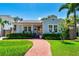 Charming blue home boasts lush landscaping, a brick walkway, and an inviting front porch with seating at 115 S Beverly Ave, Tampa, FL 33609