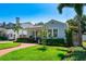 Charming blue home boasts lush landscaping, a brick walkway, and an inviting front porch with seating at 115 S Beverly Ave, Tampa, FL 33609