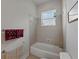 Clean bathroom featuring a bathtub with shower, tiled walls, and a window at 11530 Arlhuna Way, Dade City, FL 33525
