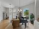 Bright living room features a grand piano, light wood floors, and a large window overlooking lush landscaping at 11530 Arlhuna Way, Dade City, FL 33525