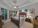 Relaxing main bedroom with tray ceiling, fan, neutral carpet, and slider leading to a sunroom at 11530 Arlhuna Way, Dade City, FL 33525