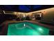 Backyard pool with verdant colored lighting surrounded by outdoor kitchen and patio seating at 12219 Steppingstone Blvd, Tampa, FL 33635