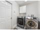 Convenient laundry room featuring modern washer and dryer units with upper cabinet storage and a neutral color scheme at 12229 Coldstream Ln, Tampa, FL 33626