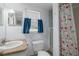 Compact bathroom featuring a toilet, sink, mirror, and a shower with cherry designed curtain at 1235 Bass Blvd, Dunedin, FL 34698