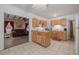 Open kitchen with wood cabinets and tile flooring flowing into the spacious living room at 1235 Bass Blvd, Dunedin, FL 34698