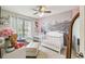 Bright bedroom featuring two white baby cribs, neutral carpet, and a large window at 13127 Topflite Ct, Hudson, FL 34669