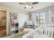 Bright Bedroom featuring a ceiling fan, window, crib, and stylish decor at 13127 Topflite Ct, Hudson, FL 34669