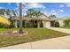 Well-maintained single-Gathering home featuring a neatly manicured lawn, mature trees, and a two-car garage at 13127 Topflite Ct, Hudson, FL 34669
