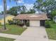 Inviting single-Gathering home featuring a neutral-colored exterior, well-maintained lawn, lush landscaping, and an attached two-car garage at 13127 Topflite Ct, Hudson, FL 34669
