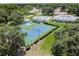 Aerial view of tennis and pickleball courts offers recreational opportunities amidst a scenic, wooded landscape at 13127 Topflite Ct, Hudson, FL 34669