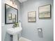 Powder room featuring a pedestal sink, framed mirror, and decorative wall art at 132 Mirror Lake N Dr # 501, St Petersburg, FL 33701