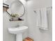 Modern bathroom features a sleek pedestal sink, round mirror with shelf, chrome towel bar, and a neutral color scheme at 13306 Wildgrass Trl, Odessa, FL 33556