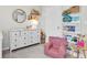 Bright Bedroom featuring a white dresser with changing top, round mirror, open shelving, and comfortable -sized armchair at 13306 Wildgrass Trl, Odessa, FL 33556