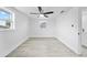 Bright bedroom with modern ceiling fan, grey flooring, freshly painted white walls, and two windows at 13715 Maria Dr, Hudson, FL 34667