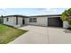 Charming home featuring a concrete driveway leading to a modern black garage door and a welcoming entrance at 13715 Maria Dr, Hudson, FL 34667