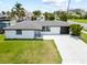 Inviting single-story home with a spacious front yard, a black garage door, and a concrete driveway at 13715 Maria Dr, Hudson, FL 34667