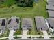 Aerial view of several residences showcasing neighborhood with well-maintained lawns and nearby pond at 13919 Wineberry Dr, Dade City, FL 33525