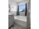 Bright bathroom with a tub under a window with blue curtains and tiled shower at 13919 Wineberry Dr, Dade City, FL 33525