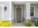 Covered front porch featuring stone accents, classic lighting, and a gray front door at 13919 Wineberry Dr, Dade City, FL 33525