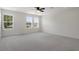 Large main bedroom featuring carpeted floor, ceiling fan, and three sunny windows at 13919 Wineberry Dr, Dade City, FL 33525