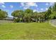 A large backyard boasts ample green space with mature trees, perimeter fence, and playground at 1460 Kensington Woods Dr, Lutz, FL 33549