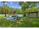A backyard featuring a playground, lush green lawn, trees, and a charming pergola at 1460 Kensington Woods Dr, Lutz, FL 33549