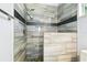Elegant walk-in shower boasts gray tiled walls, dark accent strip, and stone-look floor at 1460 Kensington Woods Dr, Lutz, FL 33549