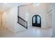 Light-filled foyer with tile flooring, wrought iron staircase, and elegant arched doorway at 147 Bay Point Ne Dr, St Petersburg, FL 33704