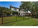 Beautiful home with black fencing, lush green lawn, and mature trees offering shade at 147 Bay Point Ne Dr, St Petersburg, FL 33704