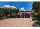 Three-car garage with brick driveway and mature trees providing shade in a sunny setting at 147 Bay Point Ne Dr, St Petersburg, FL 33704