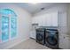 Modern laundry room with stainless steel washer and dryer, white cabinets, and unique tile flooring at 147 Bay Point Ne Dr, St Petersburg, FL 33704