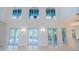 Bright living room featuring high ceilings, tile floors and multiple French door access points to outdoor living spaces at 147 Bay Point Ne Dr, St Petersburg, FL 33704