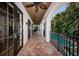 Covered outdoor patio overlooking a pool, featuring stone floors, ceiling fans, iron railings and arched entryways at 147 Bay Point Ne Dr, St Petersburg, FL 33704